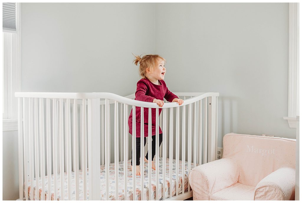 toddler-girl-jumping-in-crib-boston-newborn-photographer