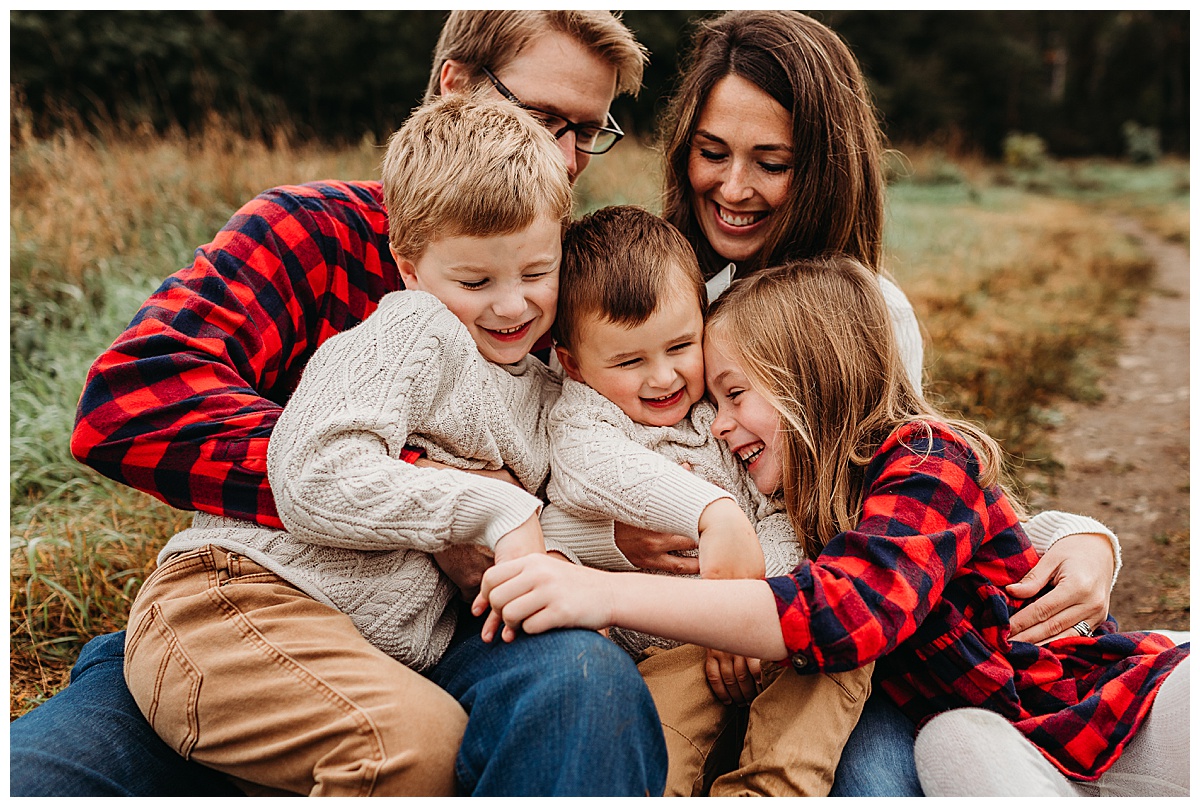 family-in-red-plaid-snuggles-on-ground-boston-family-photographer