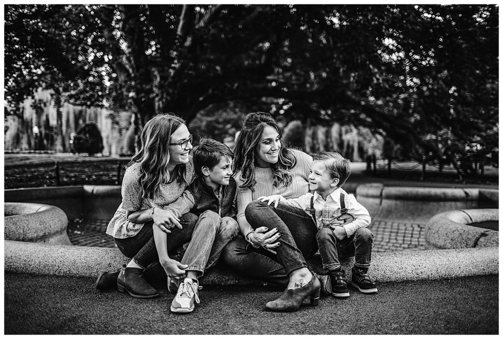 black and white portrait of a mother sitting on the edge of a fountain with her three children in the Boston Public Garden. 