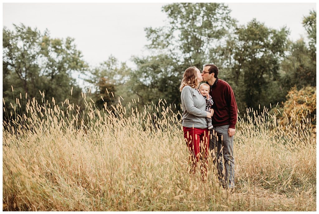 parents-with-toddler-kissing-in-golden-wheat-field-concord-family-photographer