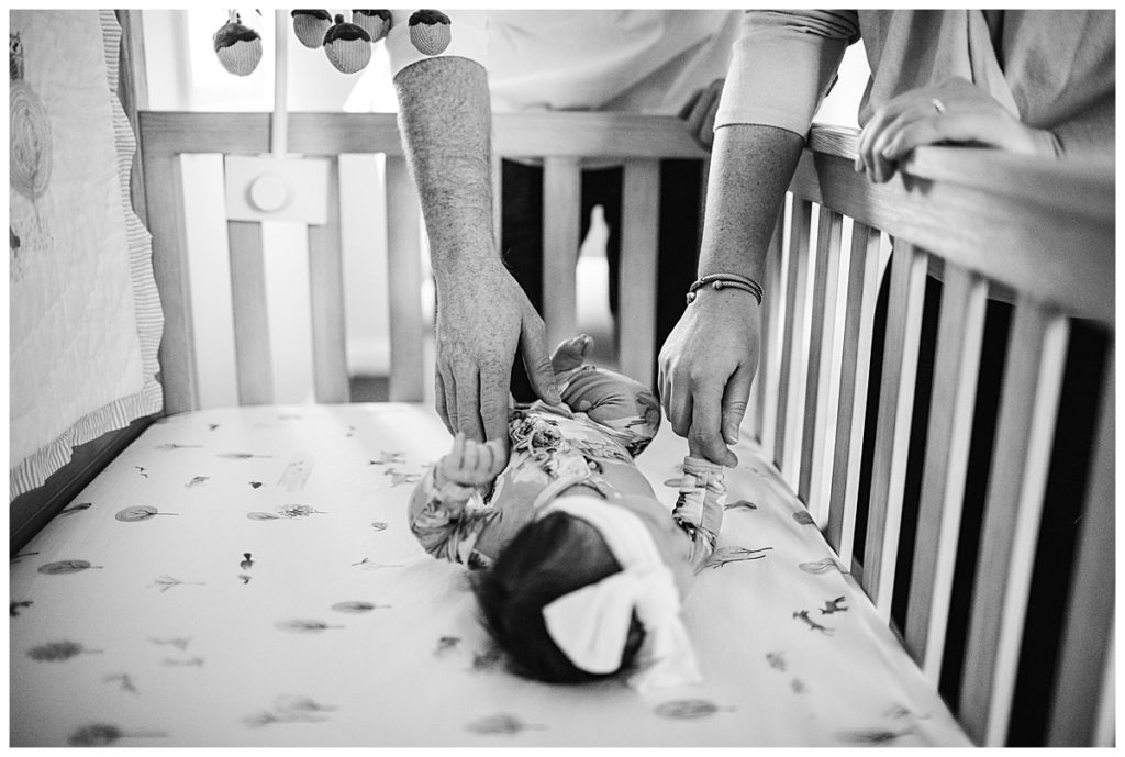 black-and-white-portrait-parents-holding-hands-with-newborn-baby-photographer