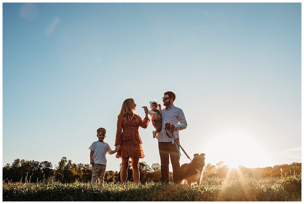Family-of-four-with-dog-standing-in-silhouette-at-sunset-boston-family-photography