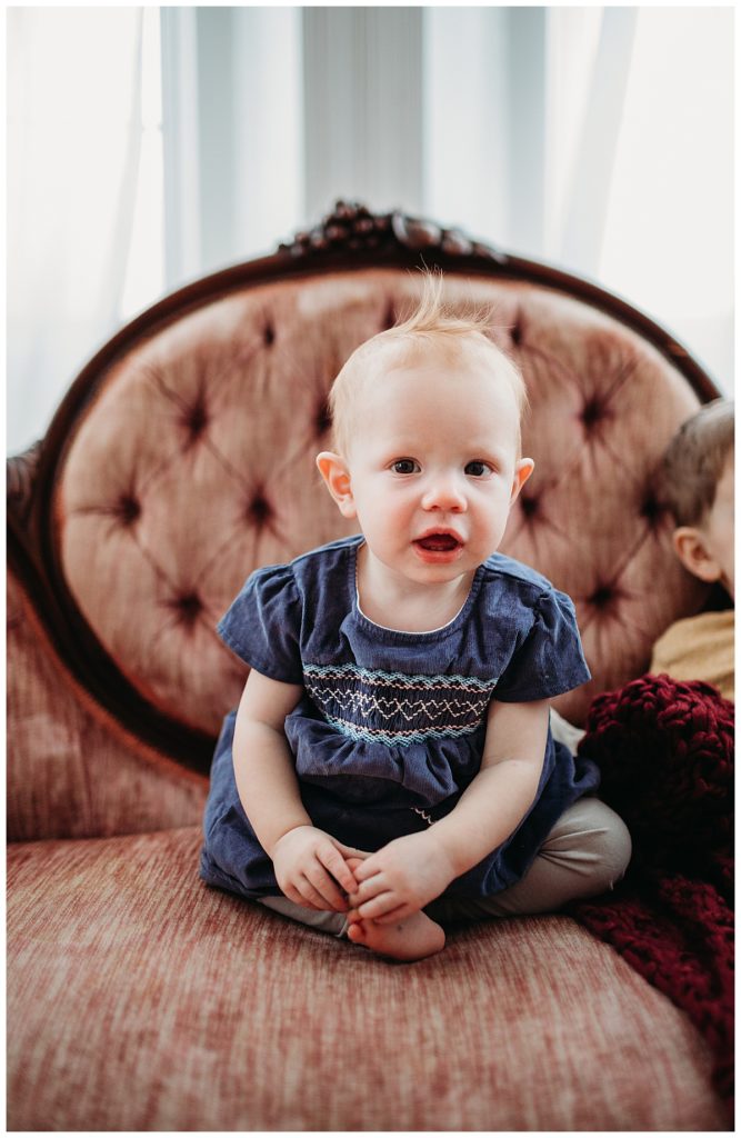baby-in-blue-dress-on-pink-couch-boston-family-photographer