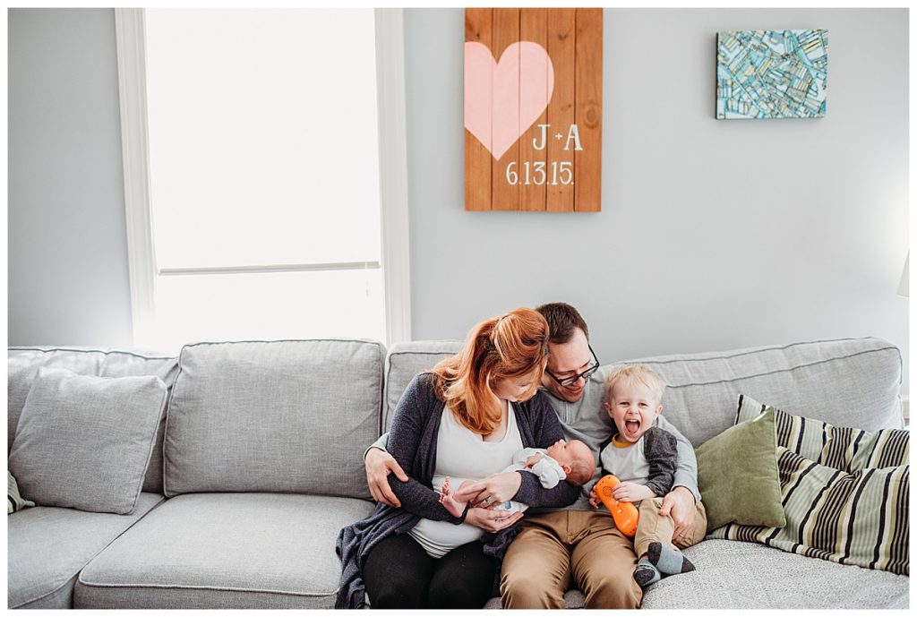 family-sitting-on-grey-couch-boston-newborn-photographer