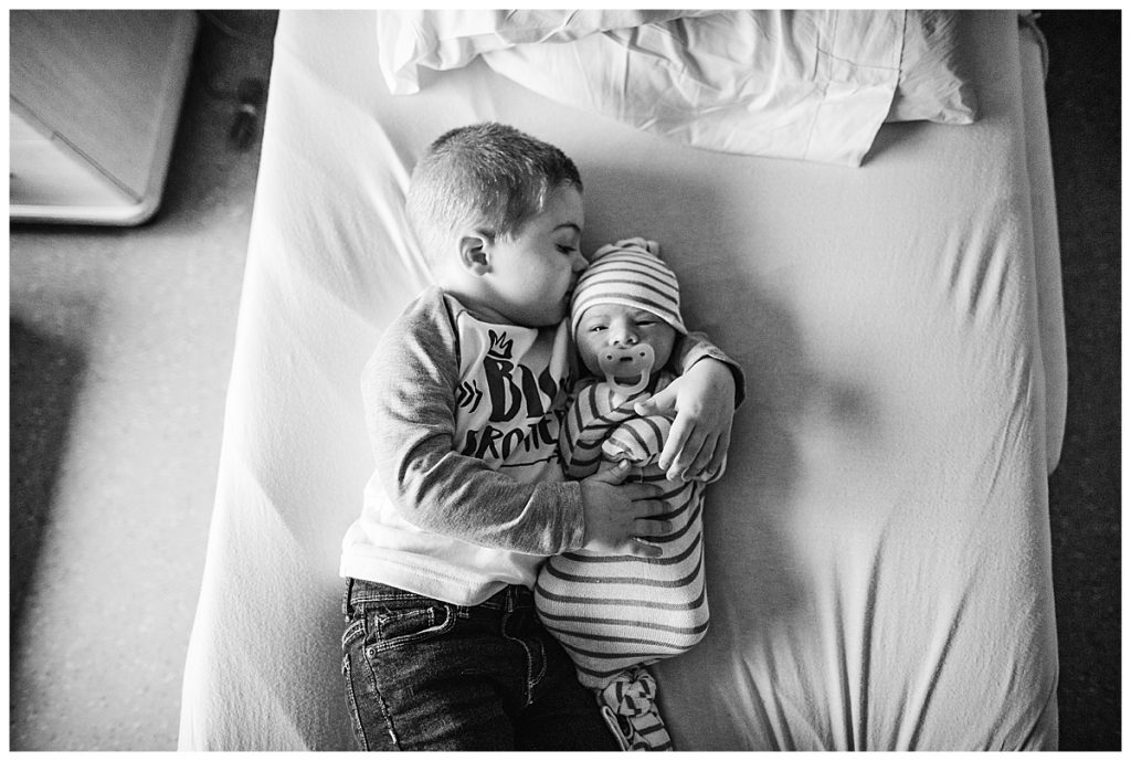 big brother holding newborn baby on boston hospital bed
