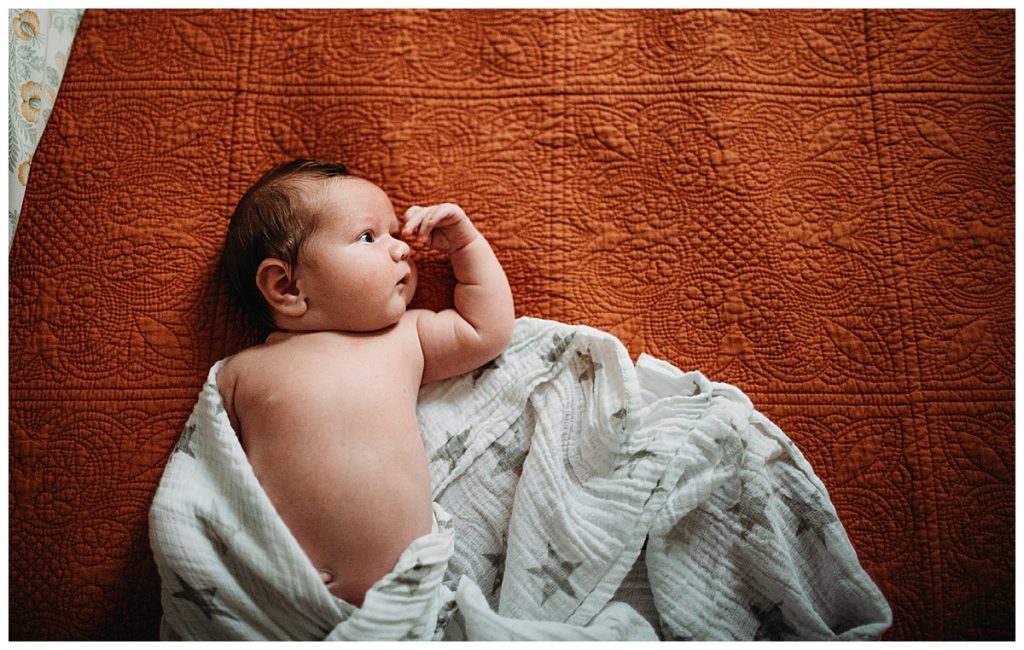 baby without clothes lying on star patterned swaddle during new mother photo session