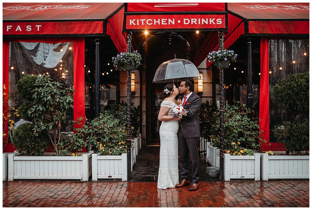 bride and groom under umbrella for rainy photos