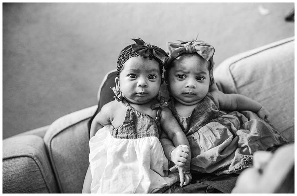 newborn twin girls in black and white looking at camera