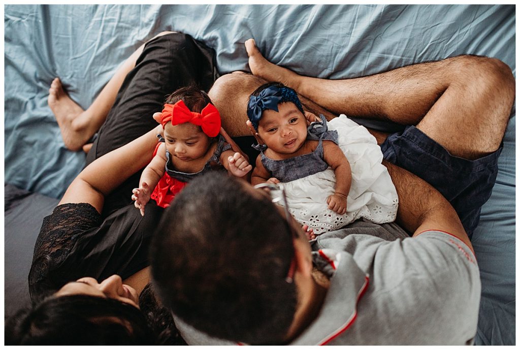 twin girls laying on parents laps during photos