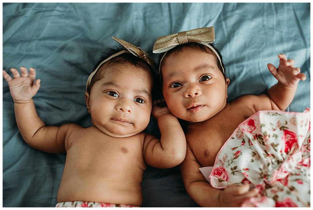 baby girls with headbands stare at camera while laying on bed