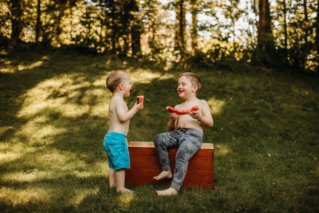 jongens eten watermeloen zonder overhemd in de zomer voor een 50mm Camera lens demo
