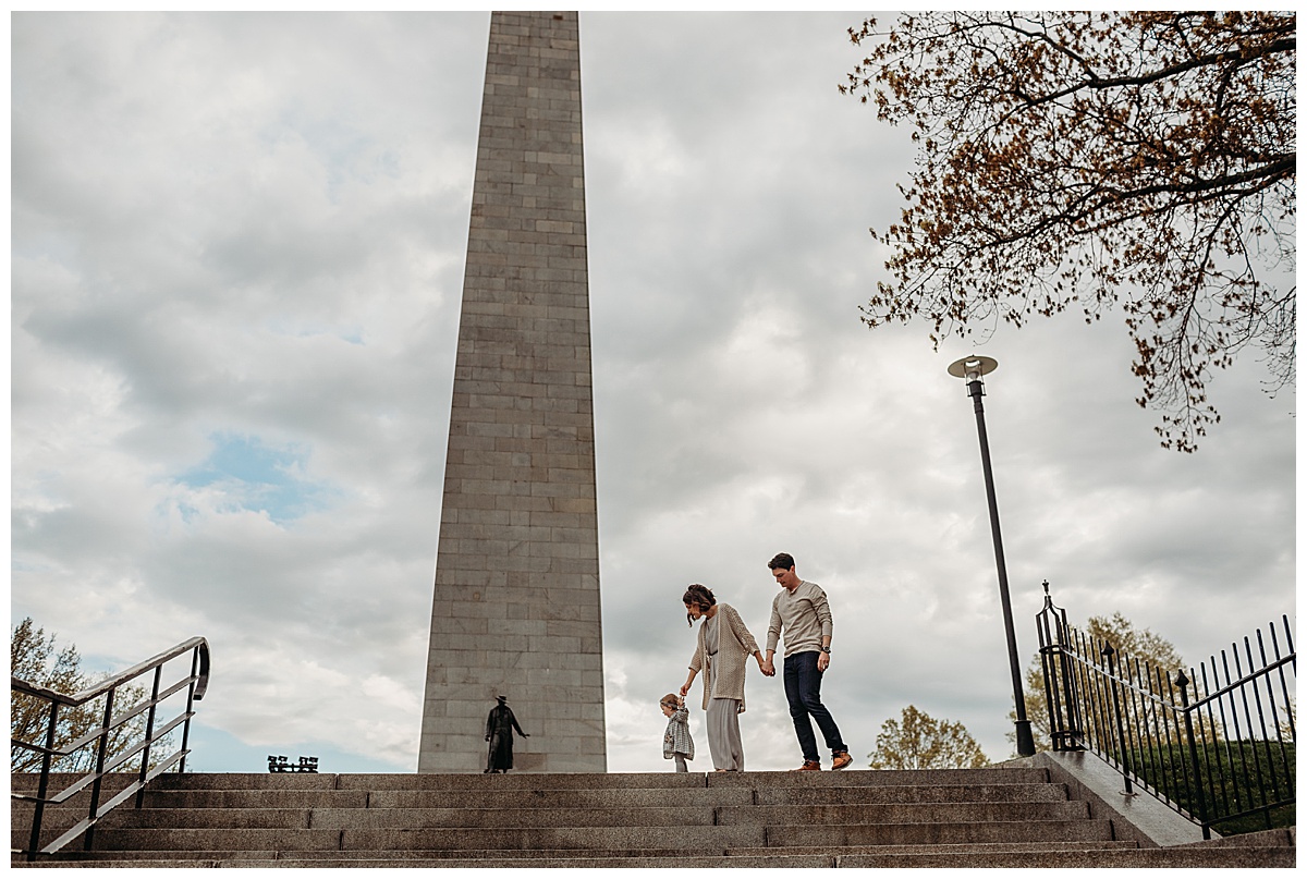 family holding hands and walking in front of the bunker hill monument in charlestown