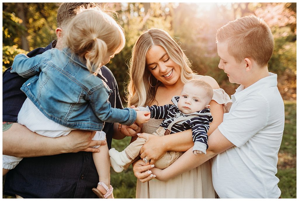 mom and family looks at baby boy during outdoor photo session