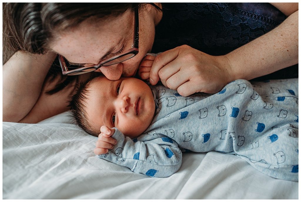mother kissing baby boy cheek during newborn photos in arlington
