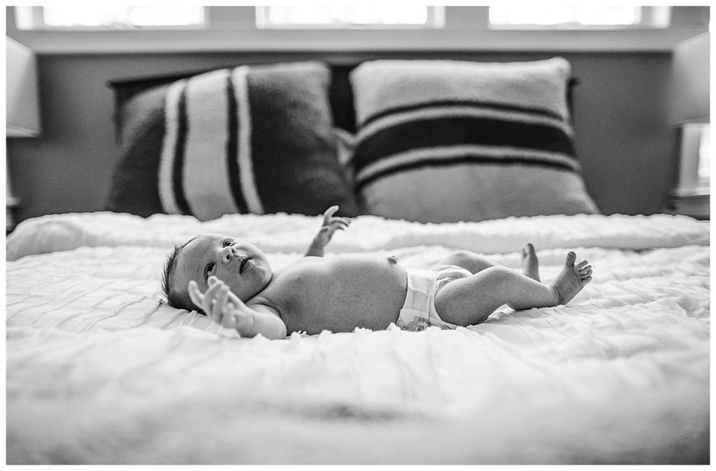 black and white portrait of newborn in diaper laying on bed