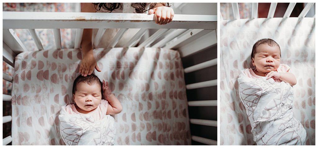 swaddled newborn lays in crib while big sister peeks through bars