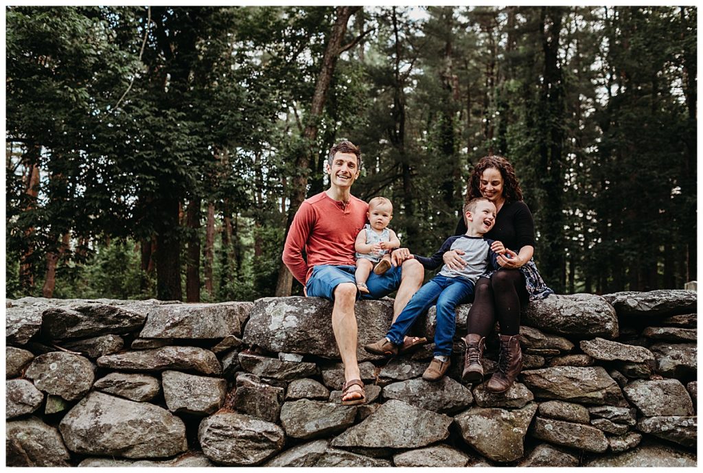 family sits on a wall during lifestyle photography pictures
