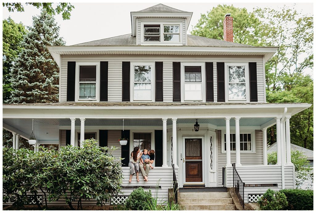 family sits on the porch of their victorian home for at-home session 