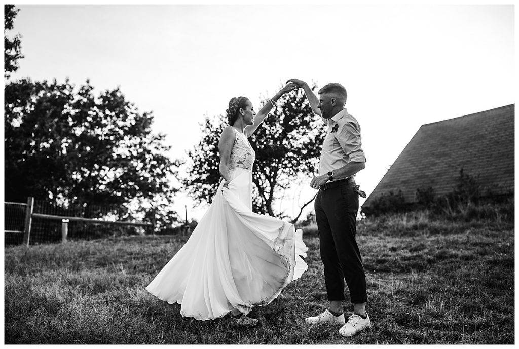 black and white image of groom twirling bride outdoors