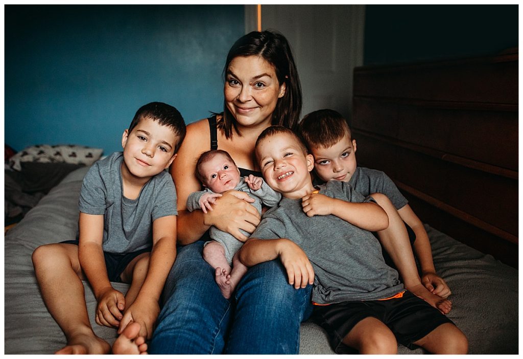 moody newborn photography of a mom with four kids