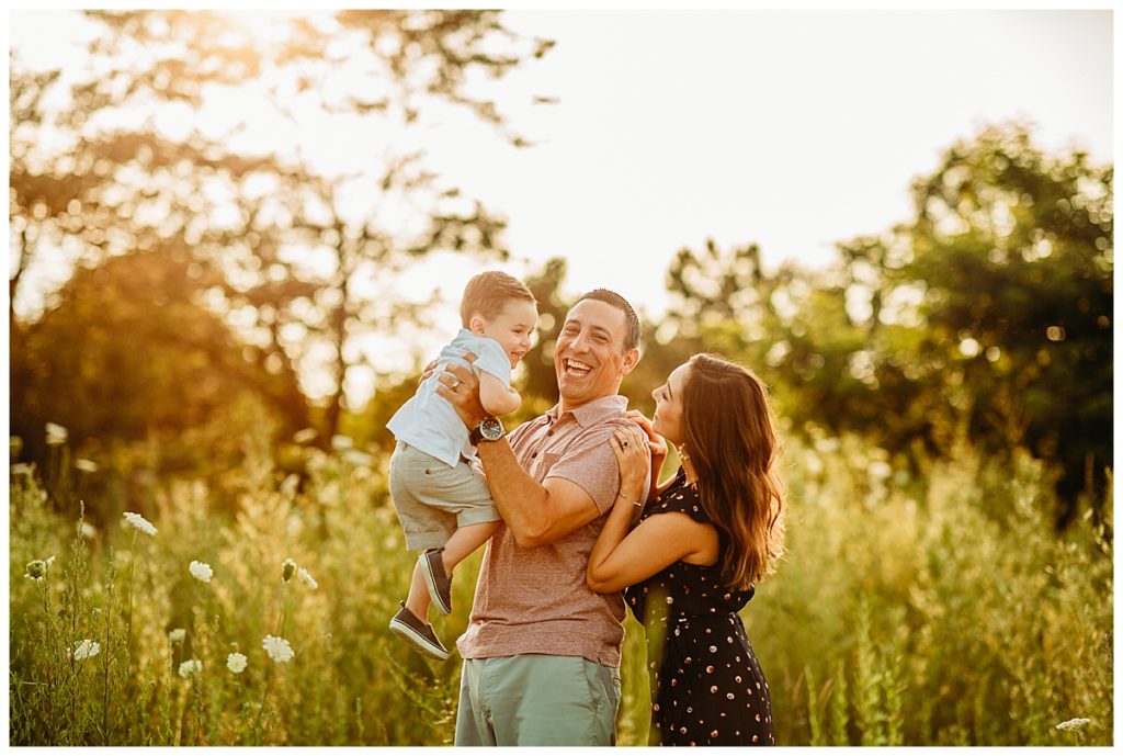 family photography myths, dad holds little boy in the air in a beautiful sunset field