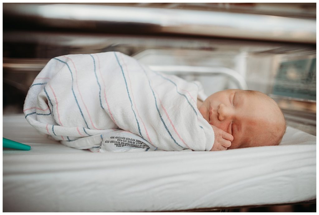 baby lays in hospital bassinet swaddled in boston hospital blanket