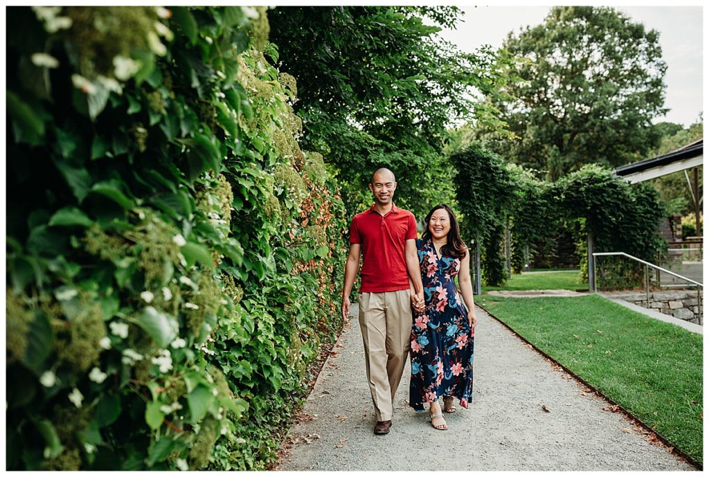 couple expecting baby walks along ivy wall in boston ma