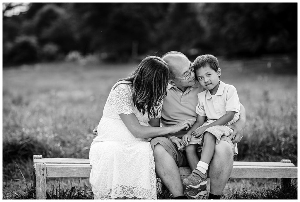 black and white image of family expecting a baby with big brother sitting on bench
