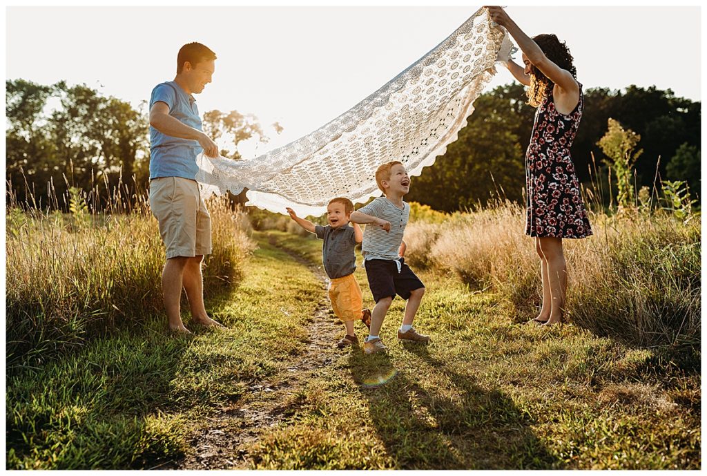 two boys run under blanket during outdoor family photography game