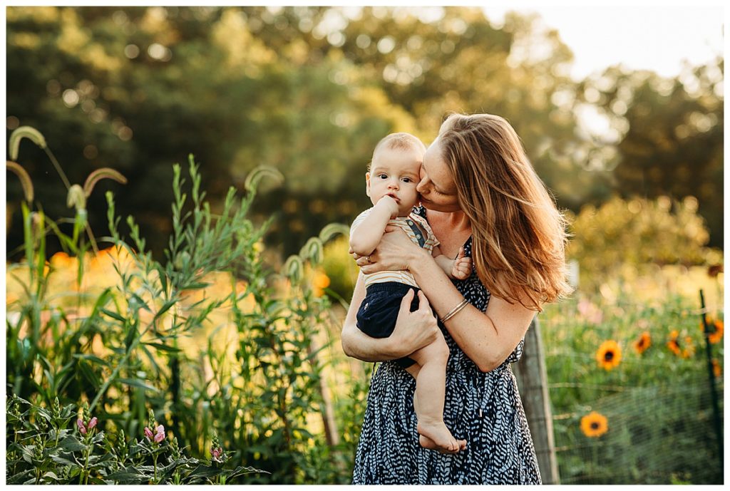 mother kisses baby in sunflower patch during an outdoor photo session