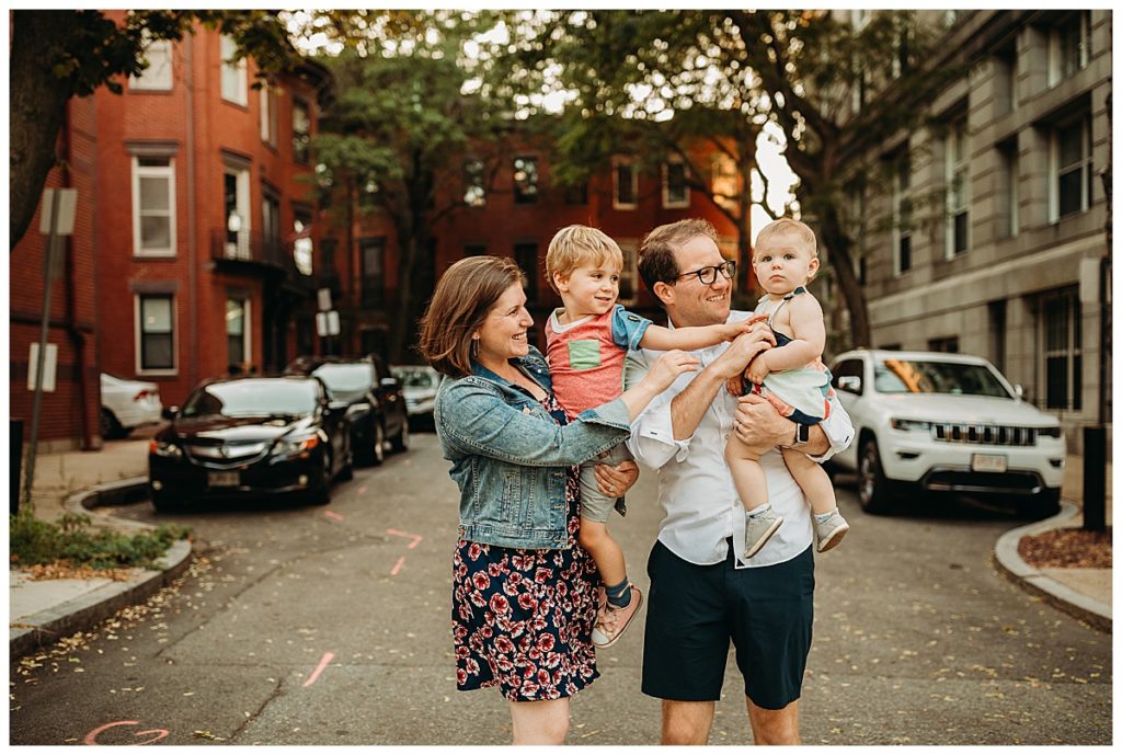 family of four tickles little sister in front of boston brownstones
