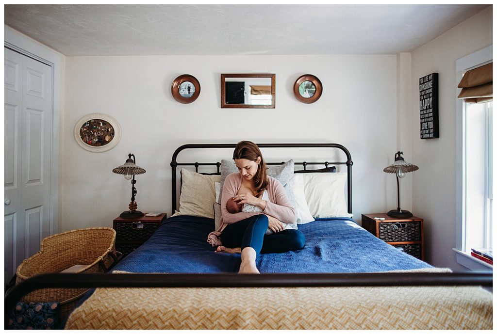 mother nursing newborn on bed with blue comforter