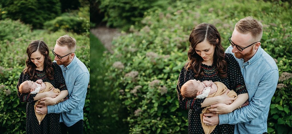 couple holds sleeping baby outdoors during family photos