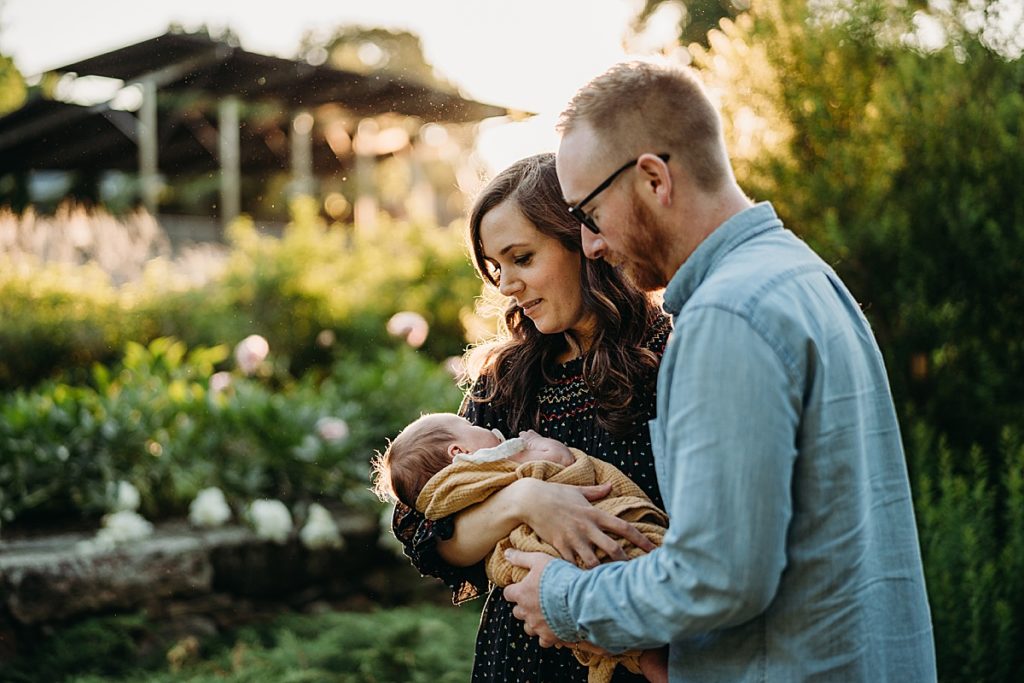 couple looks at their newborn baby girl outdoors during pictures