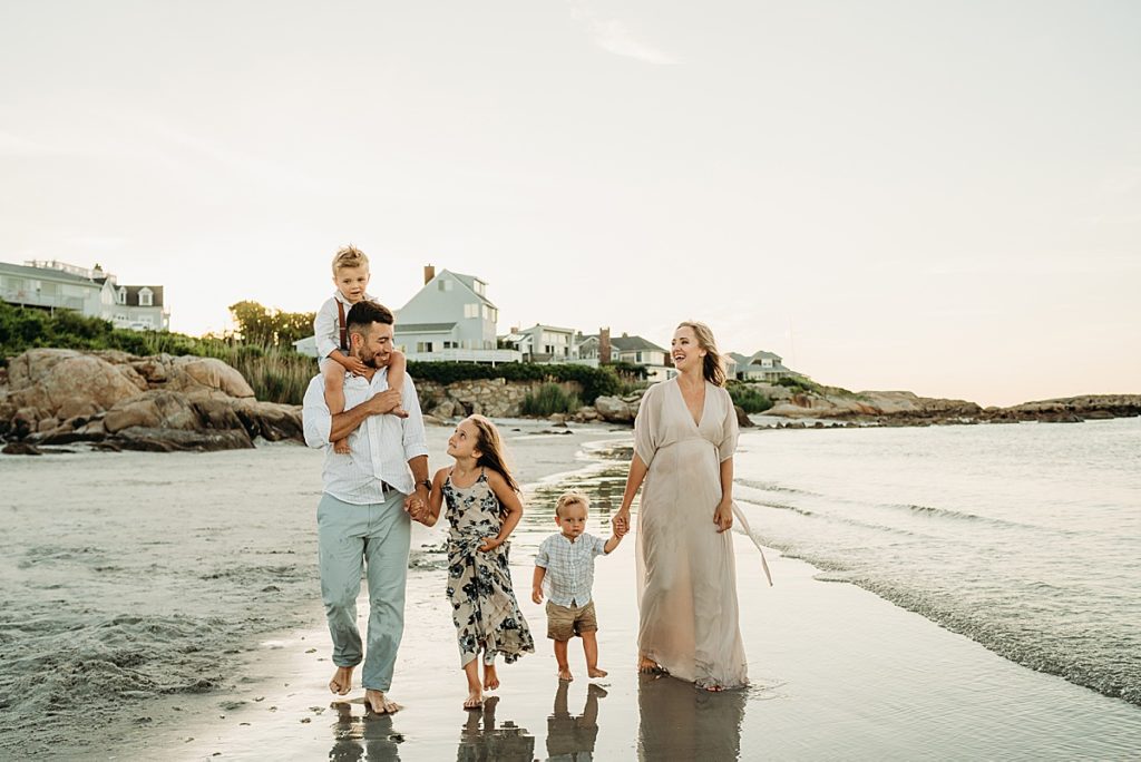 family walks hand in hand at sunset on boston beach
