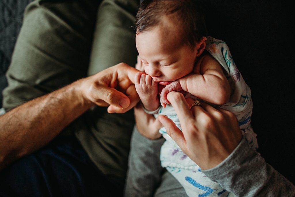 newborn baby girl holding dads fingers during baby photography session