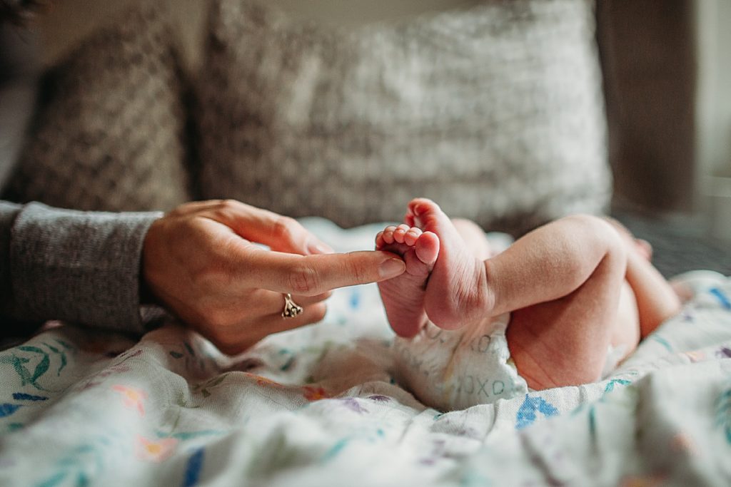 woman touches baby toes during newborn session