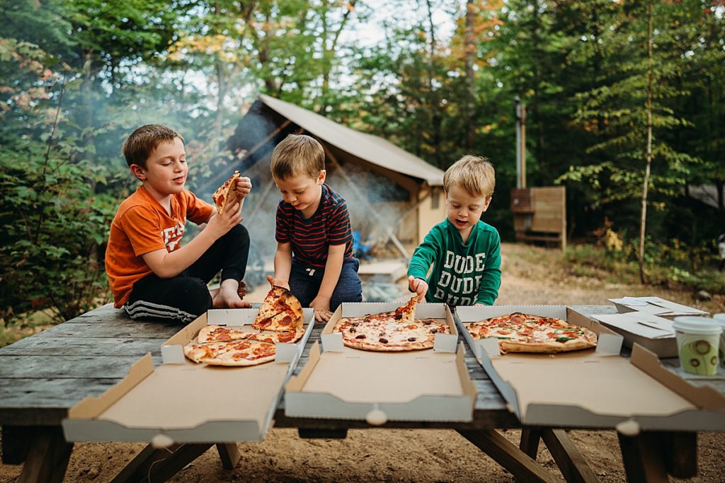boys eating pizza at a campsite