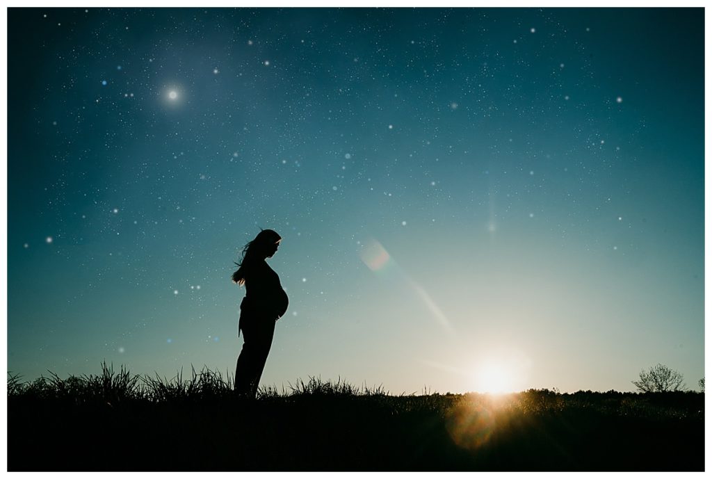 pregnant woman stands on hill with stars in sky