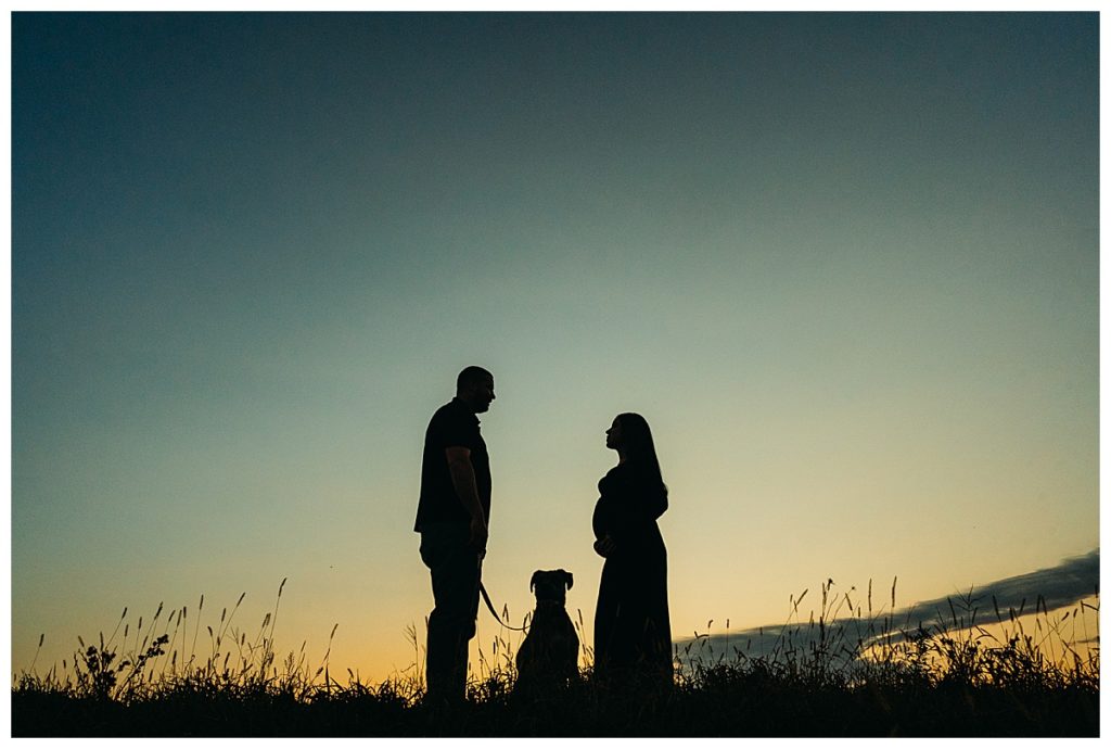pregnant couple with dog take a silhouette portrait