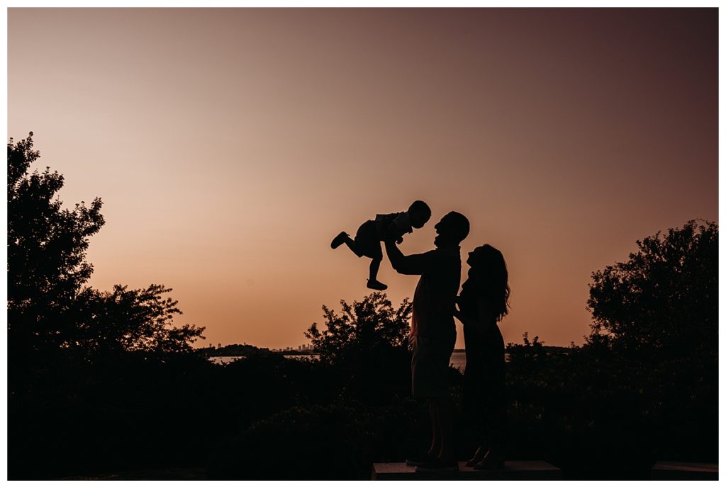 silhouette image of family of three with pink sky