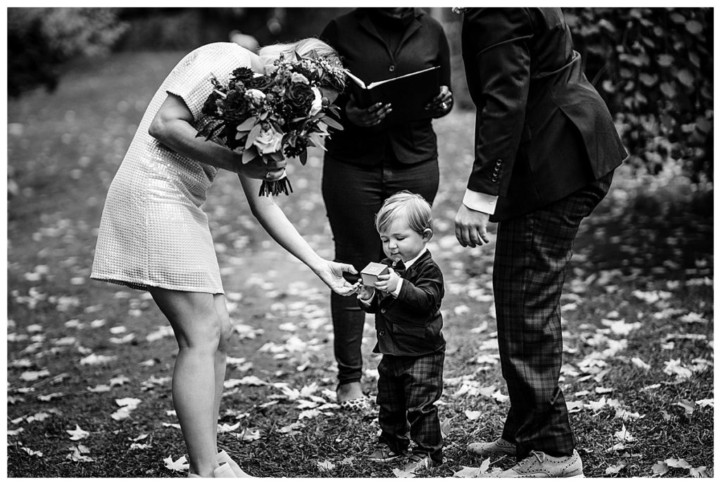 toddler ring bearer hands the rings to parents
