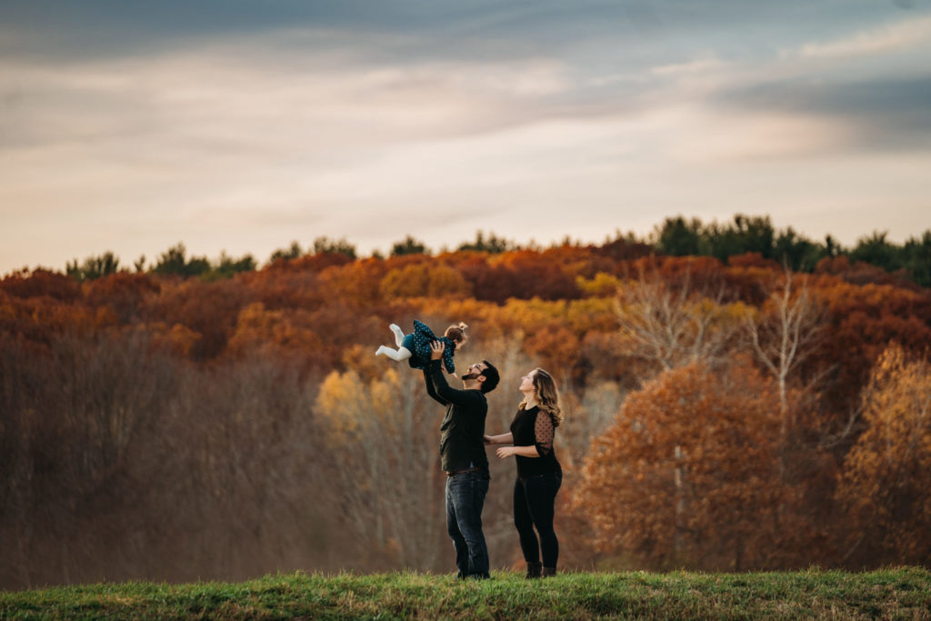 father tosses daughter in air during a boston autumn sunset evening photoshoot