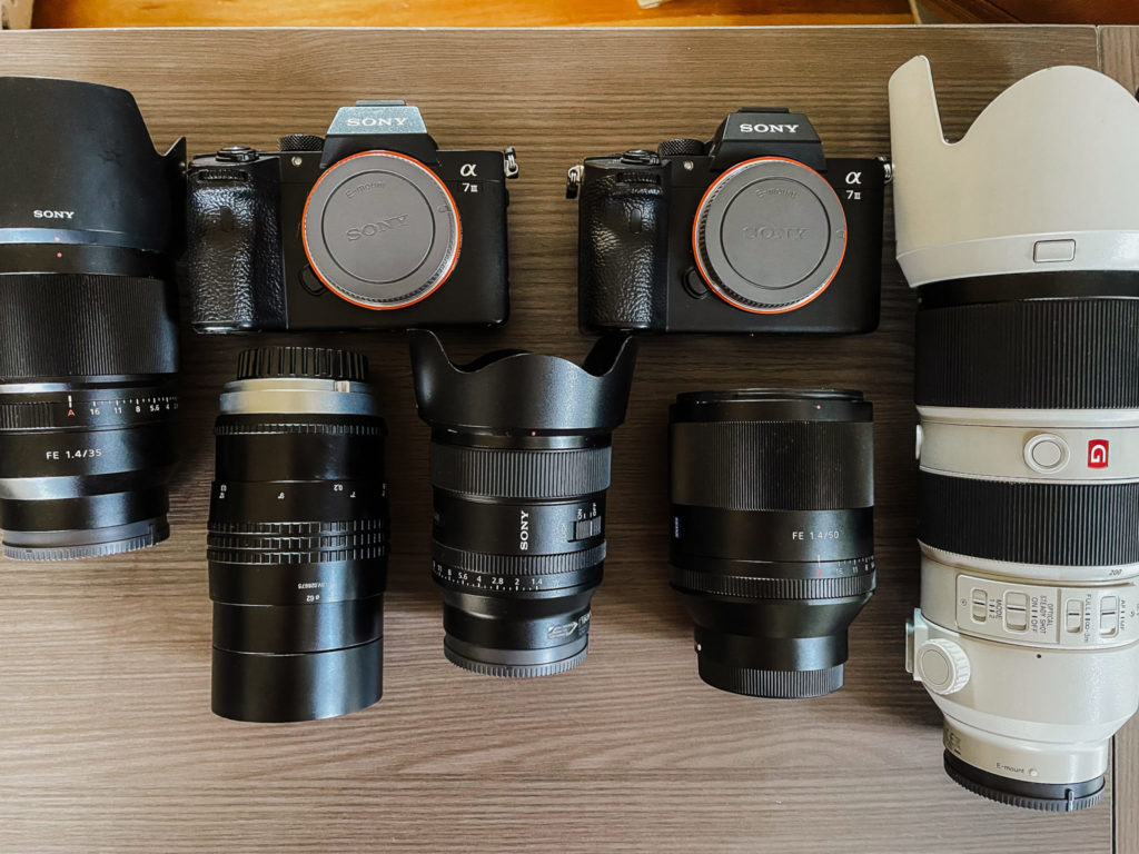 all the lenses and camera bodies that make up the content of my camera bag laid out on my desk
