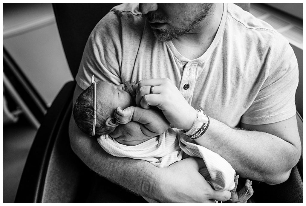 black and white image of dad putting pacifier in baby's mouth during boston newborn photos