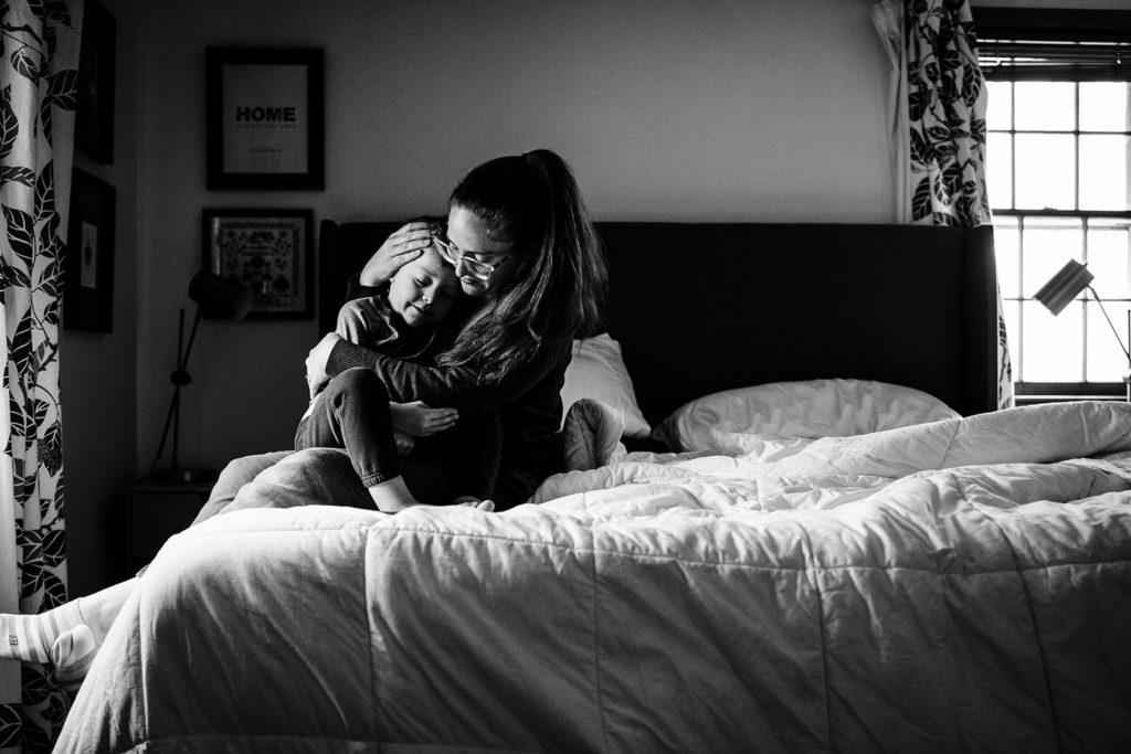 mother snuggles on bed with son while demonstrating self portraits with a sony a7iii