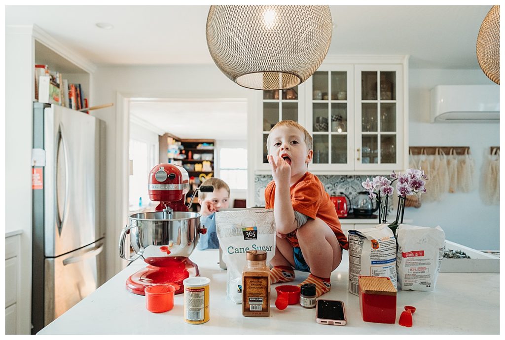 kid sits on counter while baking and licking his fingers recipes for busy parents