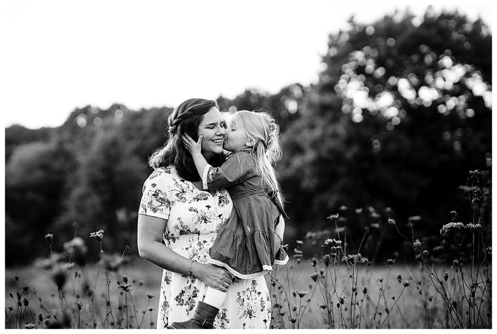black and white portrait of toddler kissing mom in boston field