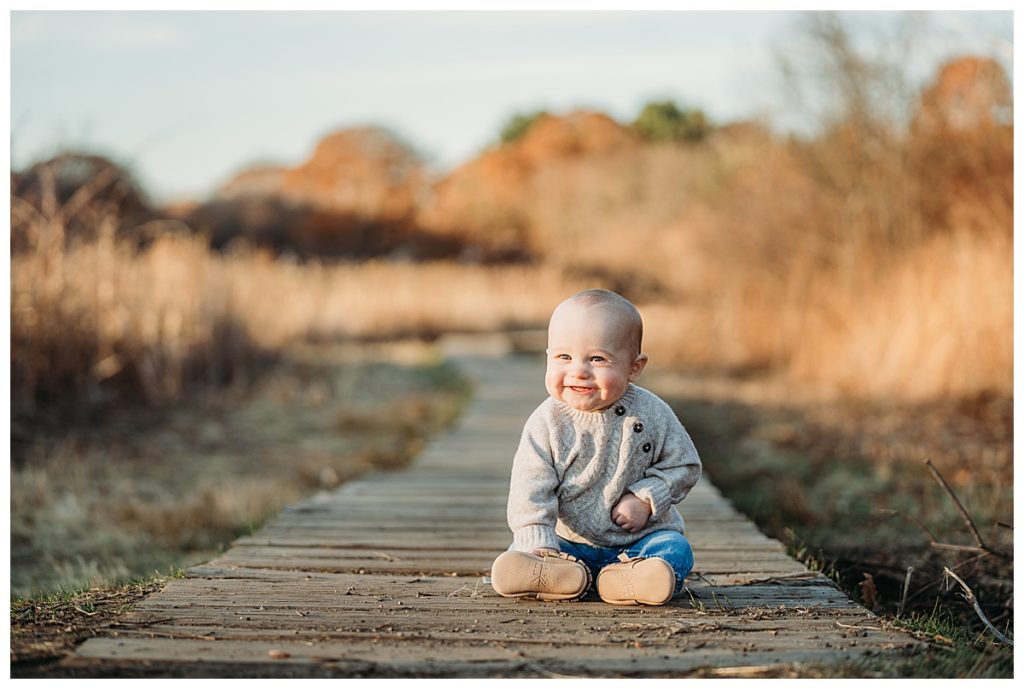six month old son sits on wooden bridge for family portraits in boston