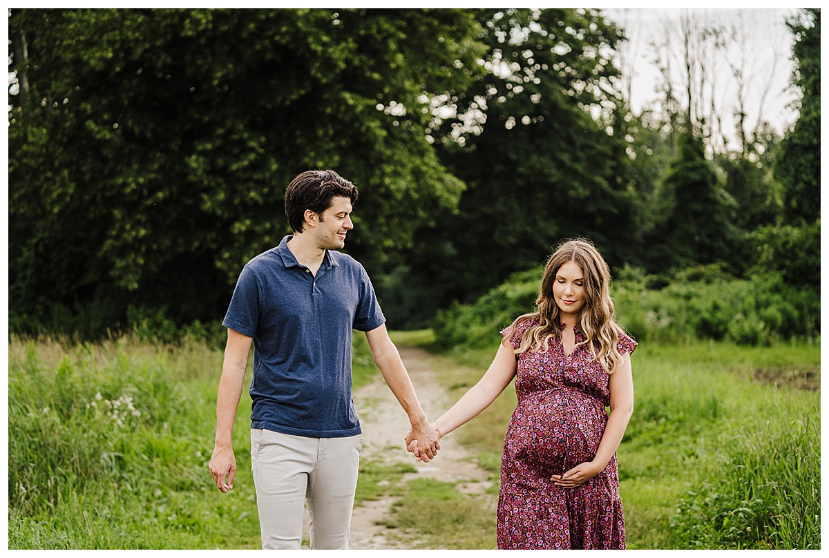 pregnant couple holds hands and walks together